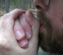 Man places both hands to his lips in a folded fashion in order to modify the sound of his labial whistle.