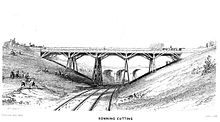 A trestle bridge on four piers spans a cutting over two rail tracks