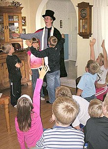Flash photo of a costumed magician at a party with several excited children.