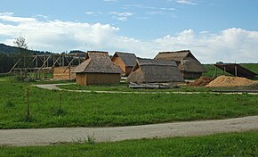 A group of wooden structures covered with shingles or thatch