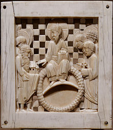 A carved ivory plate showing a bearded man with a halo around his head receiving the scale model of a church from a crowned man