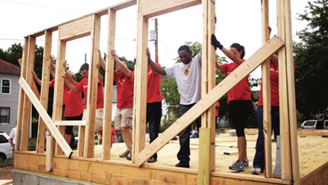 A community raises the wood framing of a new building.