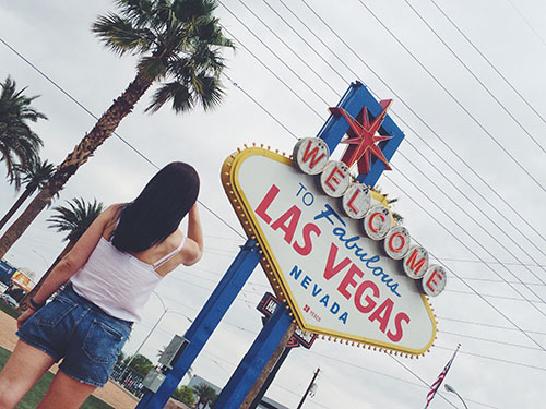 girl standing in front of welcome to fabulous las vegas sign 