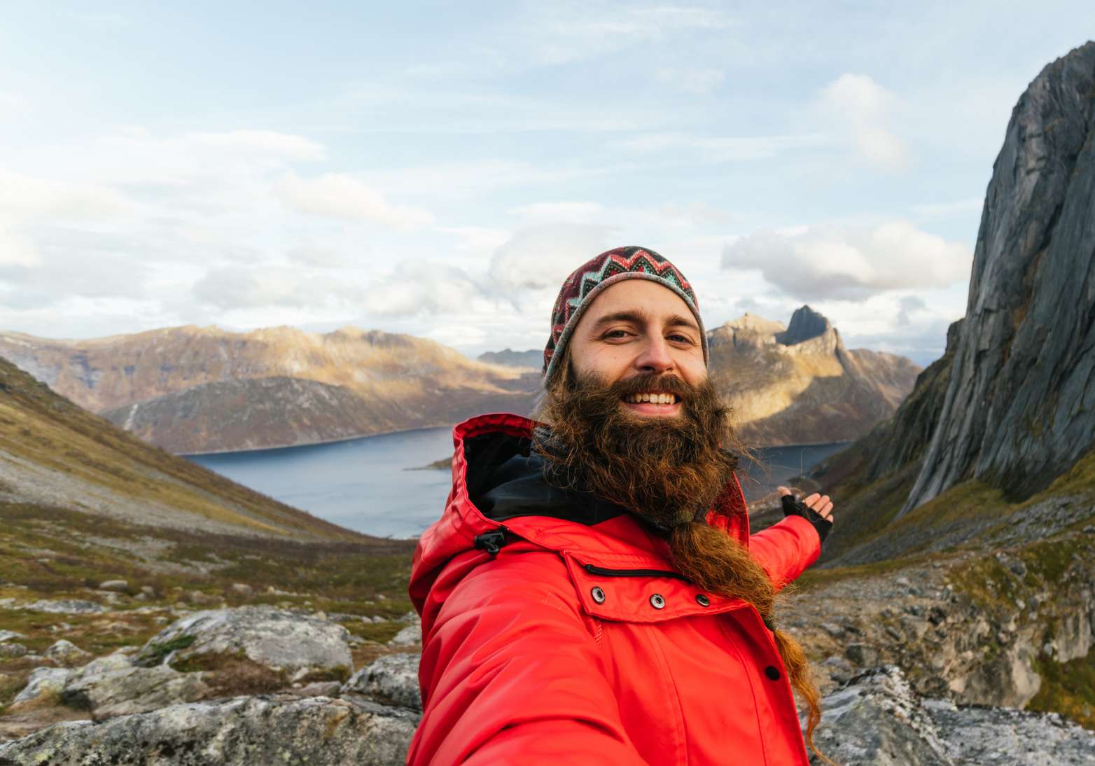 Selfie of a smiling man traveling, standing at a mountain range