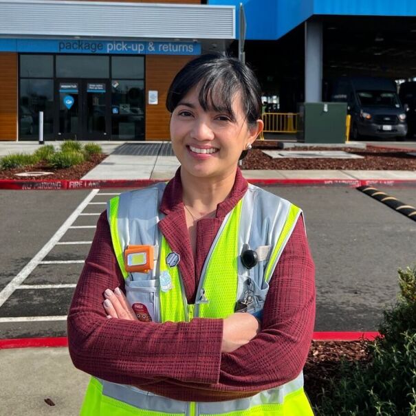 An image of a woman dressed in a yellow work vest working at an Amazon facility.