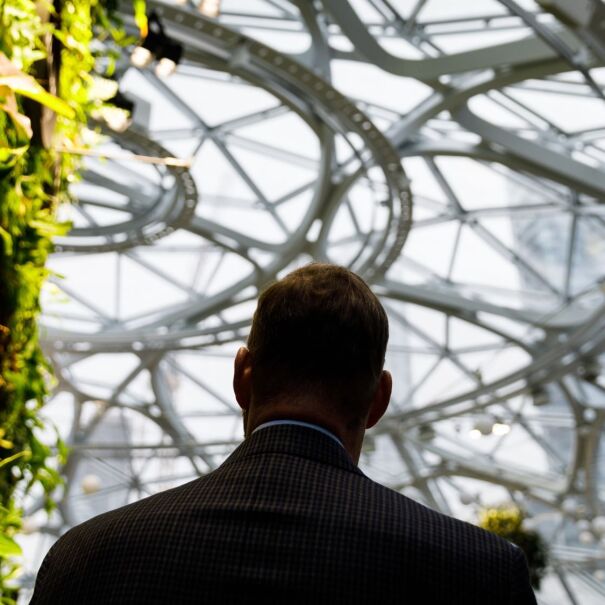 An image of the back of a man in a suit walking inside The Seattle Spheres at Amazon’s headquarters.