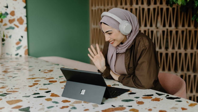 Woman wearing headphones on Teams meeting using Surface 2-in-1 laptop