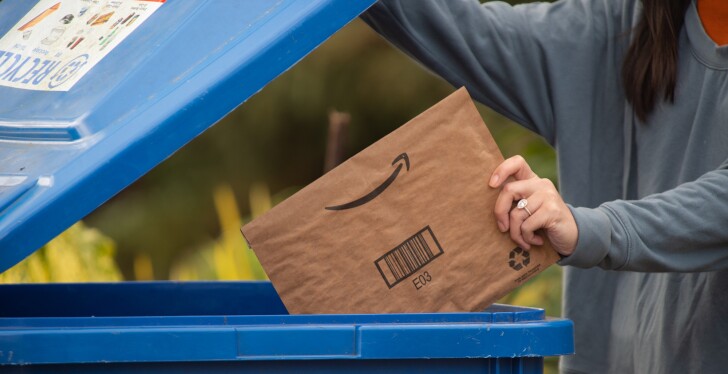 Person dropping Amazon mailer into curbside recycling bin