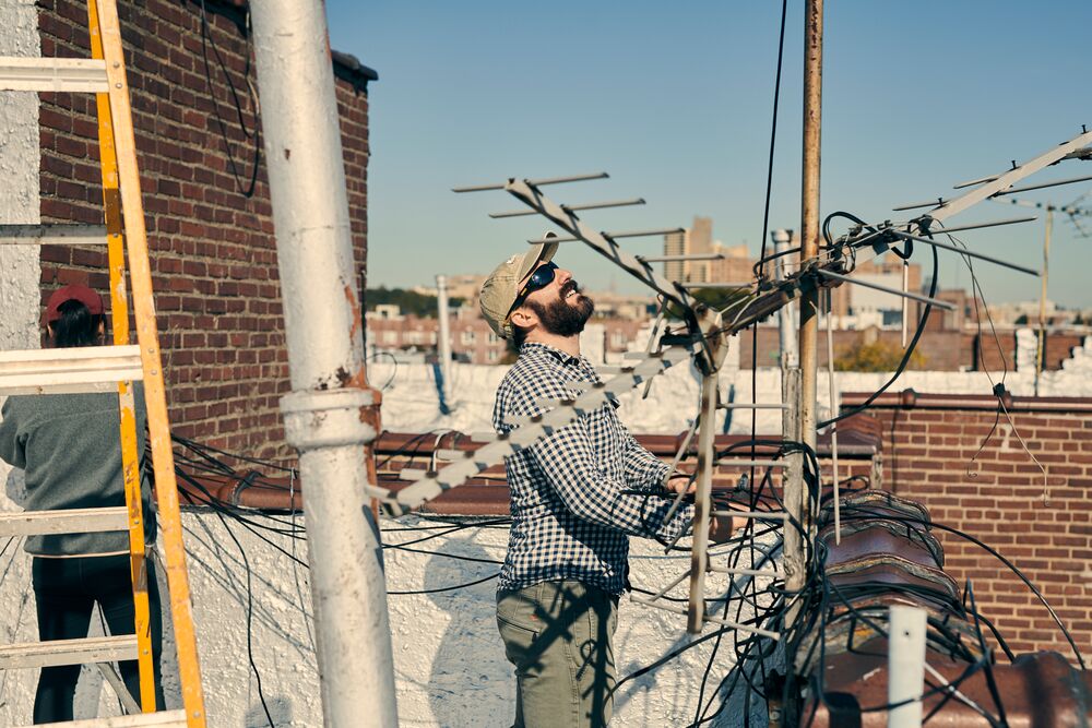 a man looking at sky next to an antenna on roof