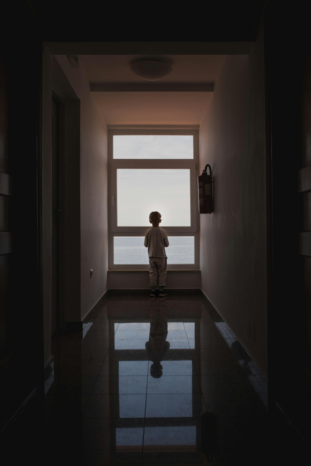 a person standing in a dark hallway looking out a window