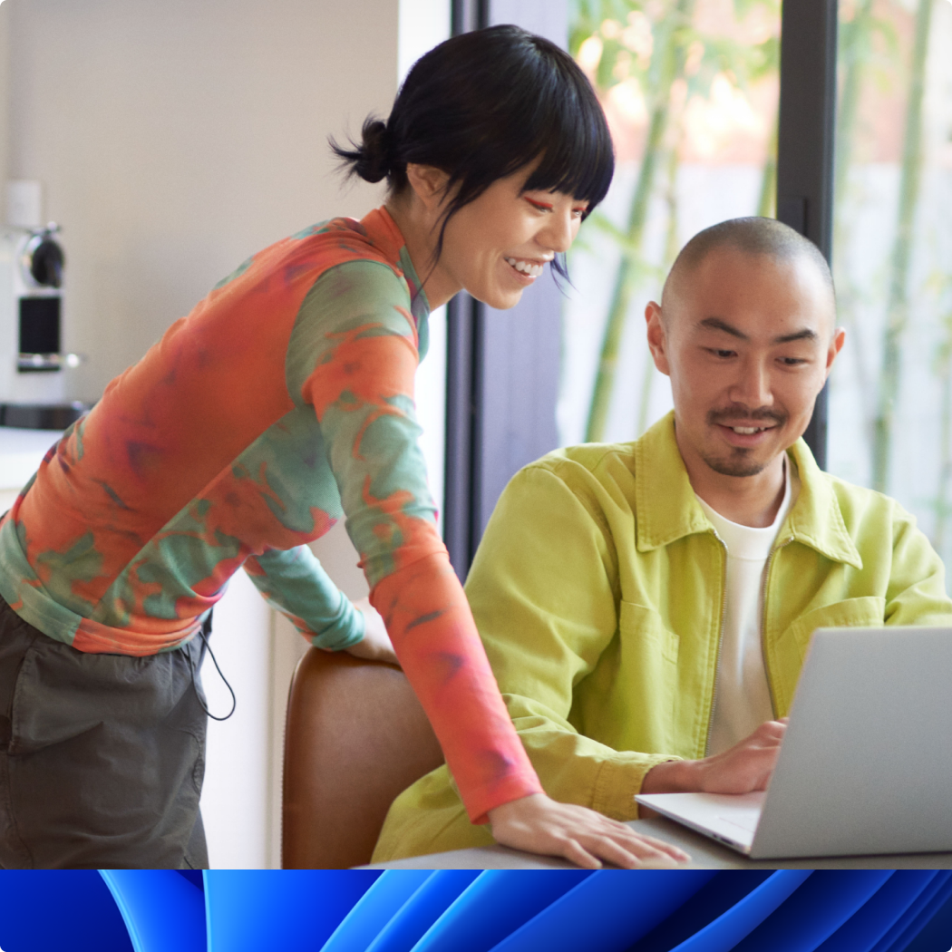 Man and woman smiling while looking at a PC