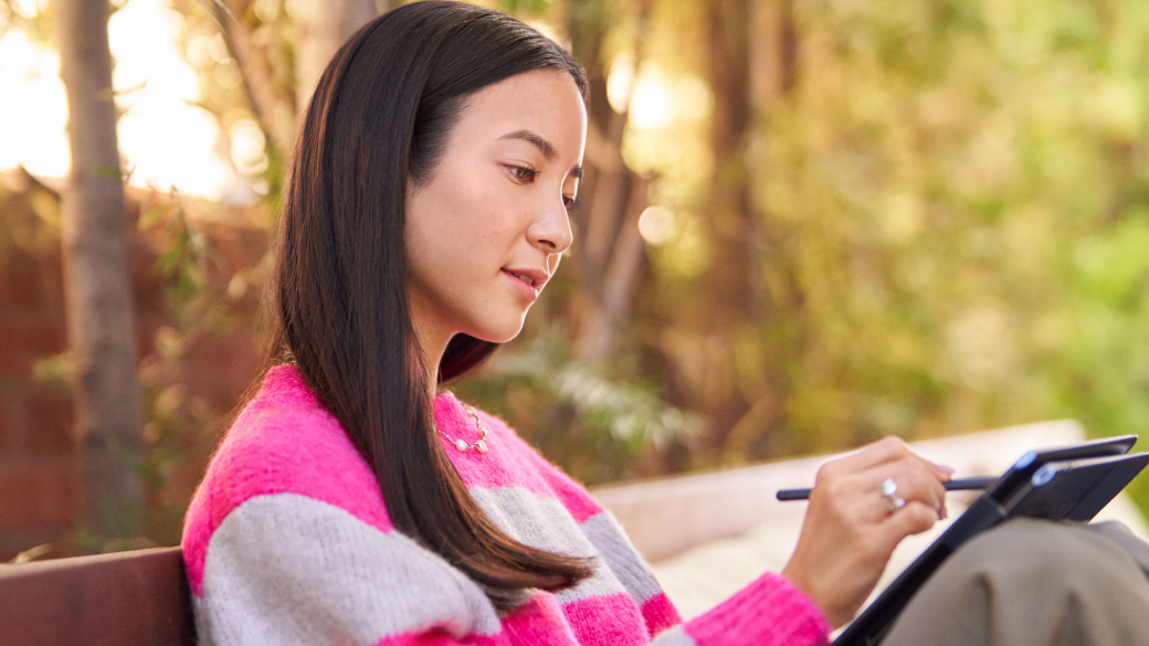 Woman sitting on a park bench using a digital pen on her PC