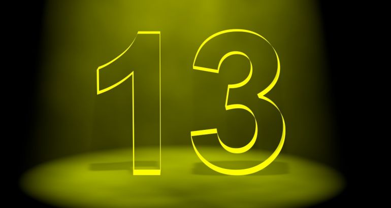 The number 13 in black lit up by yellow light on a black background.