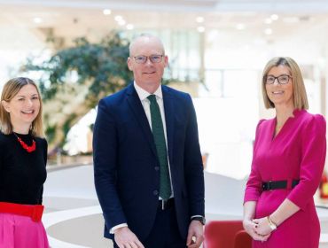 Two women from Vodafone Ireland and Irish Minister Simon Coveney standing together in a room.