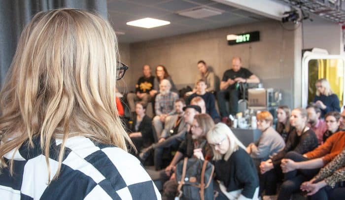 En kvinna står vänd mot en publik som sitter och lyssnar på en föreläsning i Gradängen på Goto 10 i Stockholm