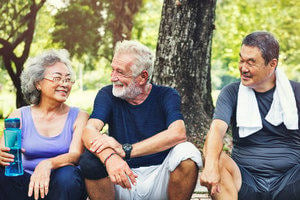 Three happy looking older people talking and resting after exercising