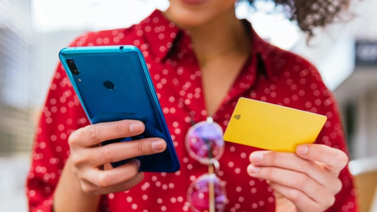 Person in a red shirt holding a blue cellphone and yellow card