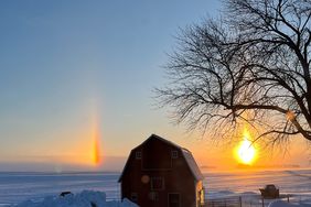 Snow covered barn with sun dogs in the sky.