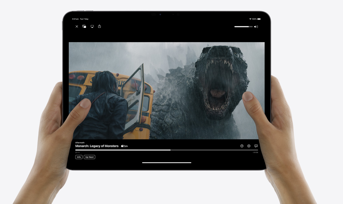 Para rąk trzymająca iPada Pro pokazującego aplikację TV, w której odtwarzany jest serial „Monarch: dziedzictwo potworów”.
