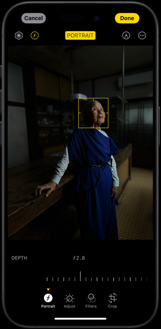 „iPhone 15 Pro“, kuriame rodomas protretas moters, nufotografuotos prietemoje su koreguojamo fokusavimo tašku ant veido