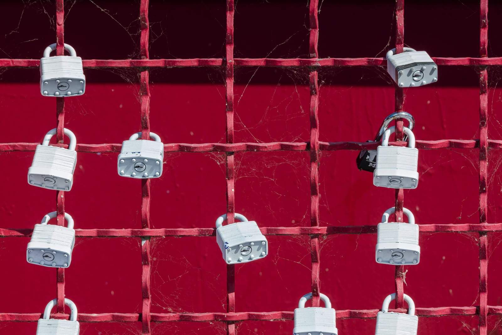 Silver locks on a red metal fence