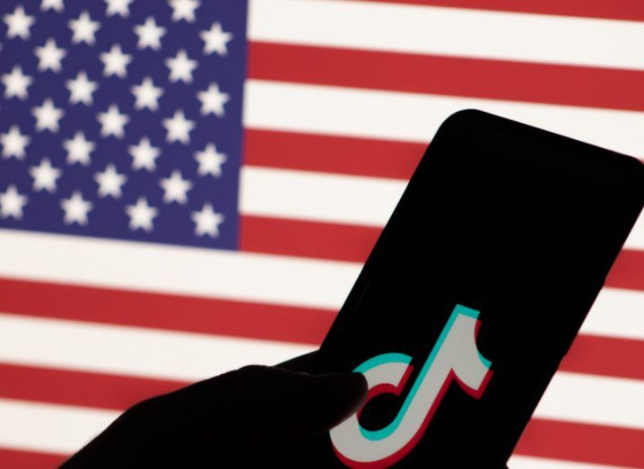 TikTok logo on a smartphone screen with a US flag in the background.